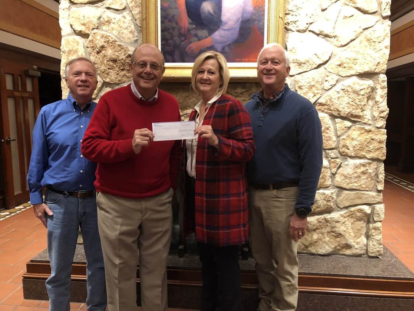 group of four posing with a check